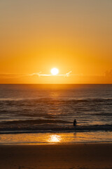 Silhouette of an unrecognizable woman entering the ocean water early in the day