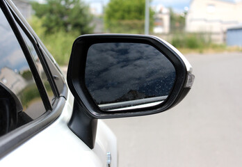 Rear-view mirror on a modern car. Rearview mirror with reflection in it. Rear view mirror car on the road. Wing mirror of a modern car with nature street. - obrazy, fototapety, plakaty