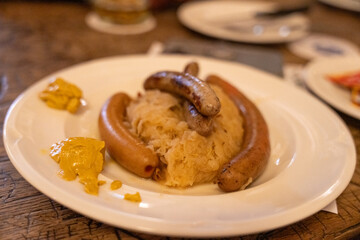 A plate of sausages and mustard sits on a table