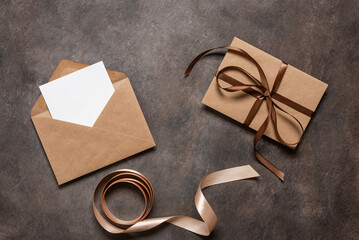 Blank card mockup in a brown envelope and a letter tied with a silk ribbon on a dark background. Top view, flat lay. - 753077762