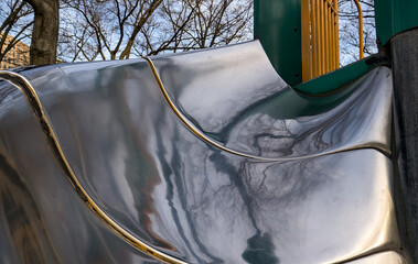 kids curved metal slide detail inside urban park playground (jungle gym in city garden brooklyn new...