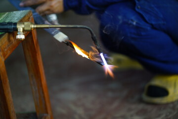 Welder working in the factory at night amidst flames and steel, wielding torches with skilled hands...