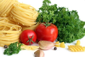 Pasta in the form of a nest with vegetables and herbs lies on a white background.	