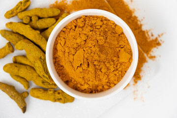 Turmeric powder, spices and dried root on white background.