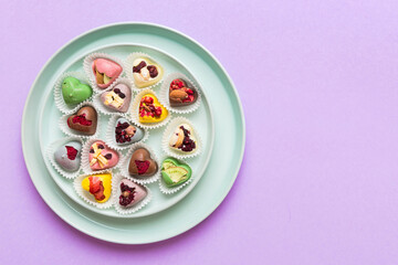 Plate with different chocolate on colored background. Assortment of fine chocolates top view vith copy space Health and obesity concept