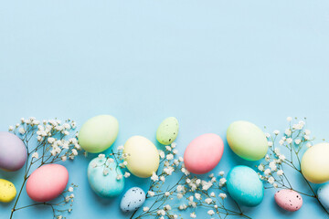 Happy Easter composition. Easter eggs on colored table with gypsophila. Natural dyed colorful eggs background top view with copy space