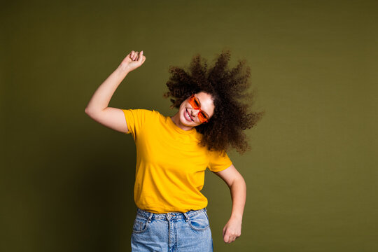 Photo of excited crazy woman in yellow t shirt and sunglasses raised fists up good vibes shaking head isolated on khaki color background