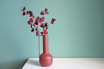 Blooming branch in a modern ceramic vase on a white table. Space for your text.