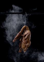 Spiced duck or Pot-stewed duck are hung by the stainless hooks with smoke