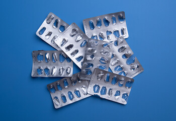 Used empty pill blister pack, discarded silver medicine packs, on blue background
