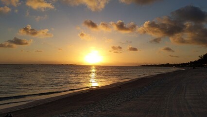 Serene Sunset Beach with Golden Reflections and Distant Shoreline