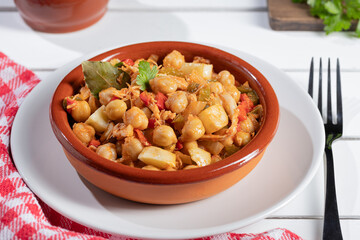 Close up. Ropa vieja, typical Canarian dish of chickpeas stew on earthenware casserole on white table.