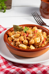 Homemade Ropa vieja, typical Canarian dish of chickpeas stew in earthenware casserole on white table. Vertical format.