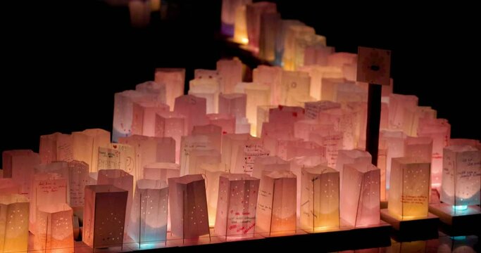 This clip captures the enchanting scene of numerous paper lanterns glowing softly in the darkness at a cultural festival called o-bon matsuri . Each lantern, possibly bearing wishes or messages