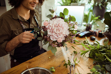 Male florist arranging a bouquet of hydrangeas in a flower shop
