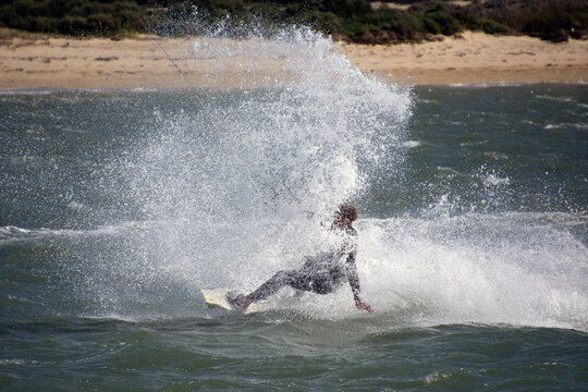 Kite surfer riding the Wind in Fuseta, Portugal. Captured in a moment of sheer exhilaration, this Fuzeta kite surfer harnesses the power of the wind to glide effortlessly over the glistening waves.