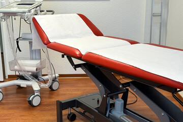 A red mobile bed covered with a paper towel in a doctor's office. Close-up.