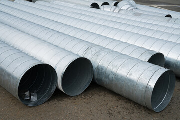 Tin pipes for ventilation installation are stacked in a row. Close-up.