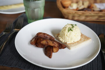 Breakfast wedges fries and scrambled eggs at the restaurant breakfast table with a cup of water.