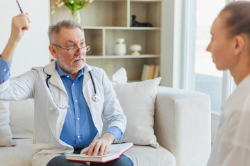 Senior man doctor examining young woman in doctor office or at home. Girl patient and doctor have...