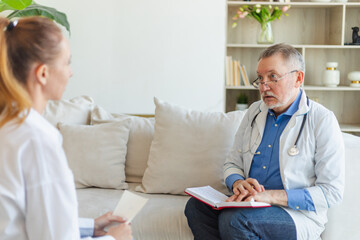 Senior man doctor examining young woman in doctor office or at home. Girl patient and doctor have...