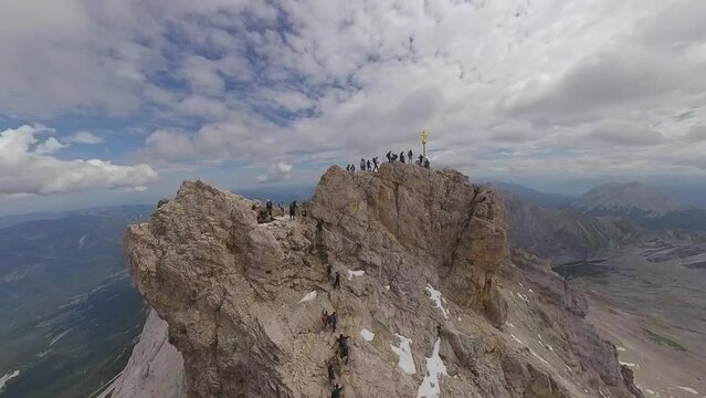 Aerial view - people climbing the summit cross of the Zugspitze, sunny summer day