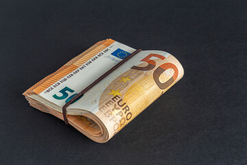 Bundle of 50 euro banknotes on a table on a black background close-up.
