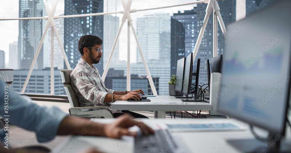 Poster portrait of a young indian business account manager working on a desktop computer in a modern corpor
