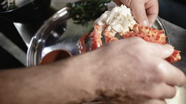 Gastronomy and seafood. Closeup view of the chef hands preparing a King Crab dish in the kitchen
