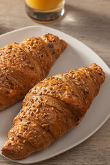 Croissants on a white plate with fresh orange juice. Close up.
