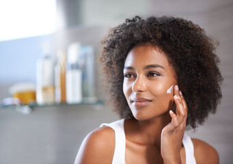 Black woman, cream on face and skincare in bathroom for beauty at home, morning routine and...