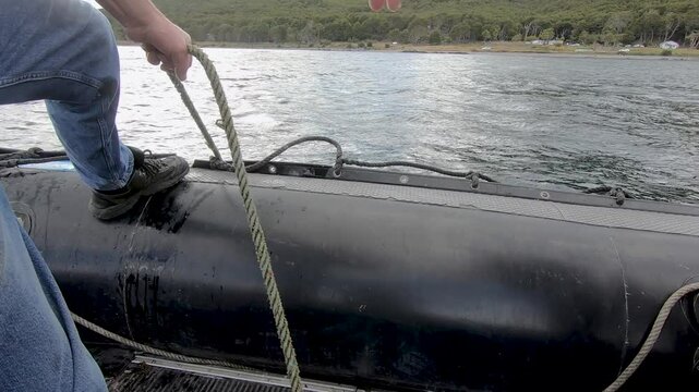 Fishing in the sea. Closeup view of a man in an inflatable boat, lifting a rope with the fishing crab trap.