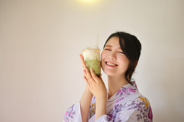 Japanese woman with yukata dress and green tea drink in hand