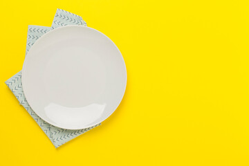 Empty plate with tablecloth on color background, top view
