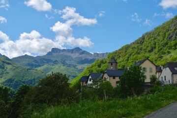 Fototapeta na wymiar Cozy distant village against vivid mountain landscape. Highland France, Pyrenees mountain range