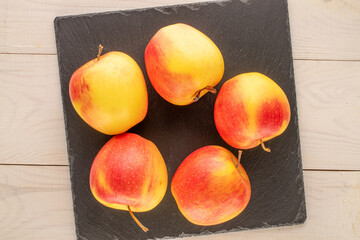 Several ripe sweet apples on slate stone, macro, top view.