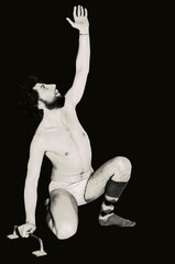 Studio shot. Caucasian young man isolated on black in his knees as pointing his hand up and holding onto a bar with the other hand.  Brush effect for Conceptual meanings.