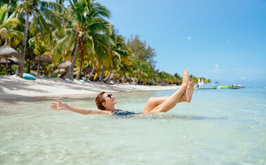 Beautiful brunette woman dressed black swimsuit in fashion sunglasses relaxing lying on shallow...