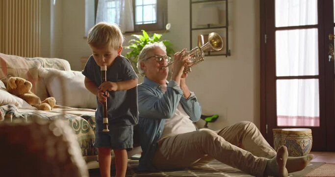 At home, at sunset, the crazy grandfather and his grandson play instruments freely.
Concept of fun, freedom and creativity