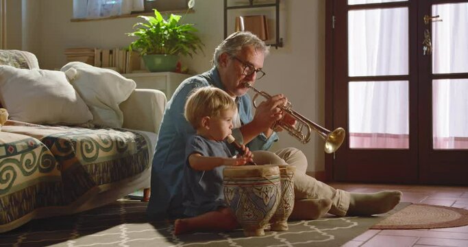 At home, at sunset, the crazy grandfather and his grandson play instruments freely.
Concept of fun, freedom and creativity