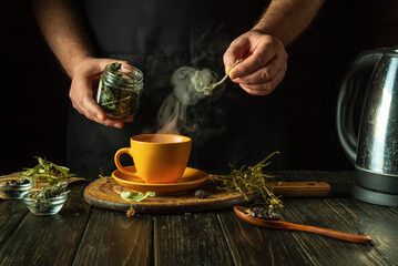 A man adds motherwort to a mug of boiling water to make a soothing tea. Traditional medicine...