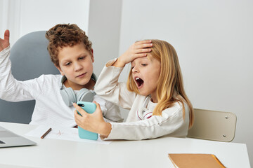 Happy Caucasian Boy and Girl Studying Online with Laptops at Home Two siblings, a boy and a girl,...