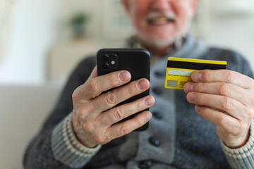 Senior man shopping online holding smartphone paying with credit card. Old grandfather buying on Internet enter credit card details. Online shopping delivery service Older generation modern tech usage