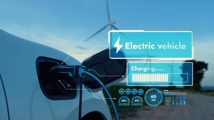 Electric car recharging energy from EV charging station display futuristic smart battery status hologram by EV charger plug cable in wind turbine farm. Alternative clean energy sustainability. Peruse