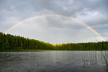 Double rainbow with main rainbow with interference arcs and secondary rainbows over Lake Helgasjön and trees in the background in Helgö National Park, Växjö, Kronobergs län, Smaland, Sweden - obrazy, fototapety, plakaty