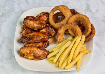 barbecue chiken wings with onion rings and french fries