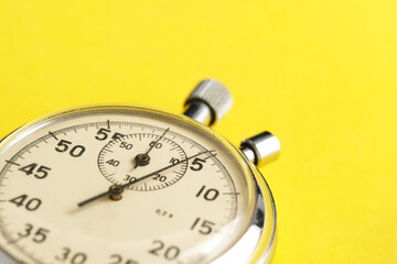 Mechanical stopwatch yellow background closeup.