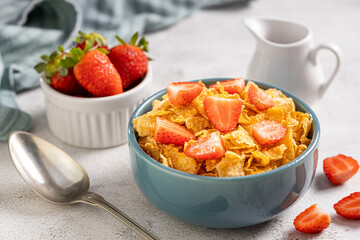 Bowl of corn flakes with sliced strawberries.