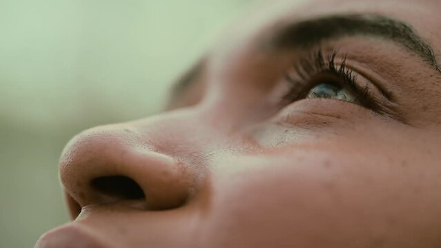 Young woman opens eye to sky in tight macro close-up of facial feature