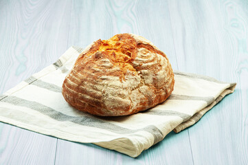 baked Italian bread on a light wooden table. ciabatta on a white towel on a wooden background	